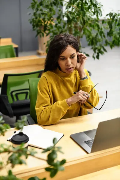 Elegant woman focused on her task in a vibrant office surrounded by plants and natural light. — Stock Photo