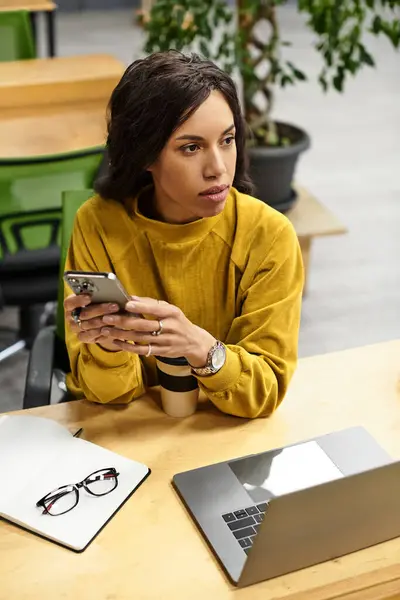 Beautiful woman in a stylish setting focuses on her smartphone, surrounded by office essentials. — Stock Photo