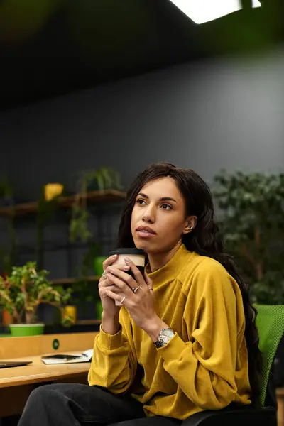 Young professional enjoys a warm beverage, contemplating ideas amid a lively workspace. — Stock Photo