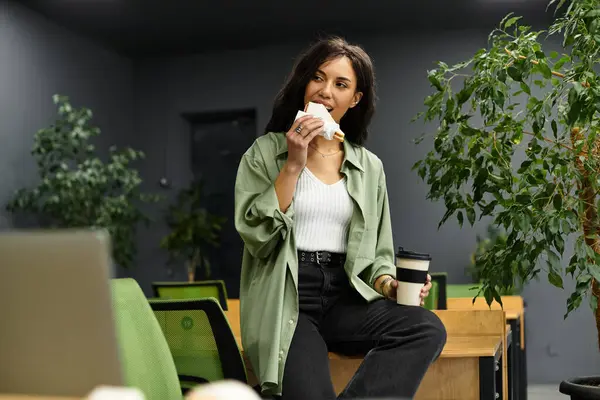 Young and beautiful professional engages in a refreshing break with food in an upscale office. — Stock Photo