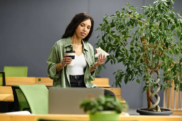 In un ufficio chic, una splendida donna si rilassa con uno spuntino e un caffè, irradiando eleganza. — Foto stock