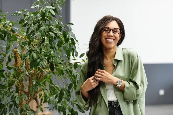 A confident woman smiles brightly in an office, showcasing her creativity and elegance. — Stock Photo