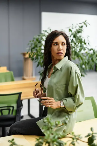 An elegant woman works at a wooden table in a modern office filled with plants. — Stock Photo