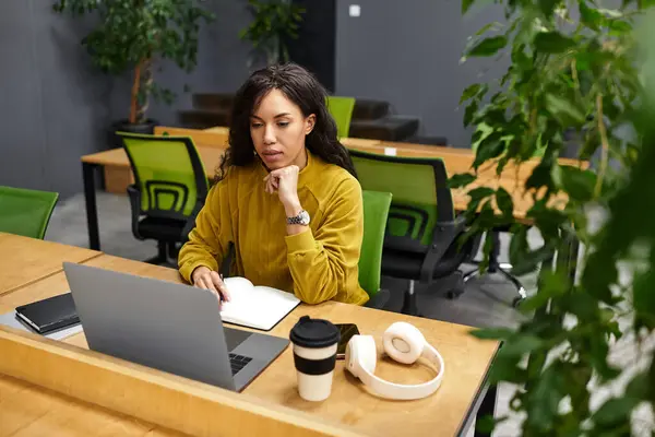 A young, elegant woman is focused on her tasks at a sleek office desk, surrounded by plants. — Stock Photo