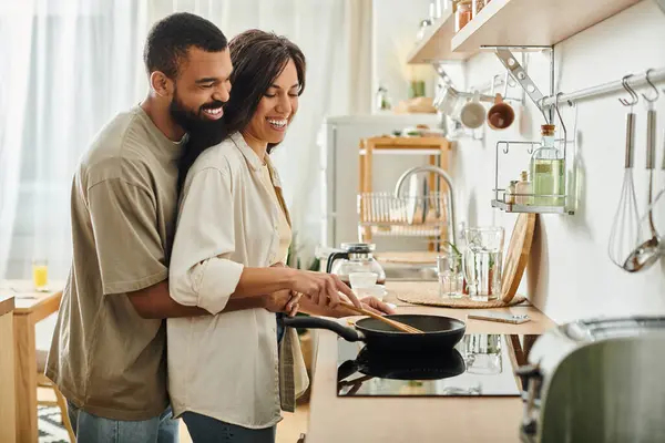 Pareja comparte risas y amor mientras cocinan juntos en su acogedora cocina. — Stock Photo