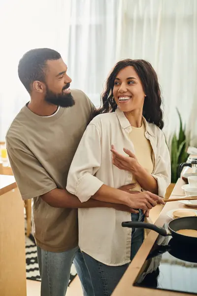 Pareja comparte un momento alegre mientras cocinan juntos en su cálido y acogedor ambiente hogareño. - foto de stock