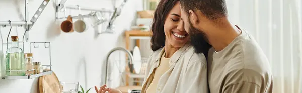 Una coppia felice condivide un momento giocoso cucinando insieme nella loro cucina calda e invitante. — Foto stock