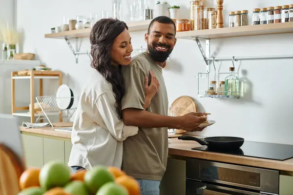 Una pareja feliz disfruta de un tiempo de calidad en su cómoda cocina, cocinando y riendo juntos. - foto de stock