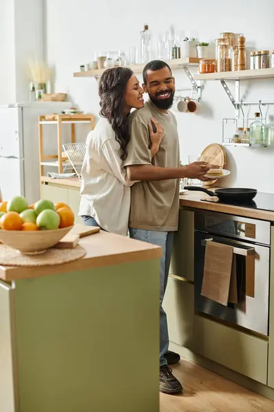 A joyful African American couple cooks together in a cozy kitchen, radiating warmth and love. — Stock Photo