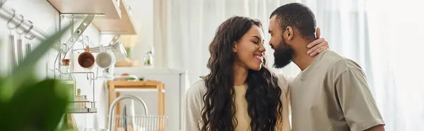 A loving African American couple shares a joyful moment in their cozy kitchen. — Stock Photo