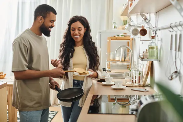 Una coppia gioiosa condivide un momento giocoso nella loro cucina calda e invitante. — Foto stock