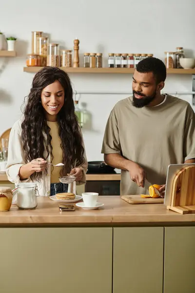 Feliz casal preto compartilha um momento amoroso ao fazer café da manhã em sua cozinha. — Fotografia de Stock
