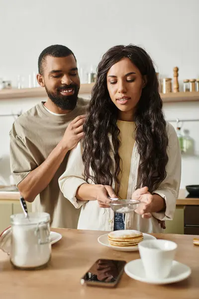 Una pareja disfruta de un momento cálido juntos en su acogedora cocina mientras preparan el desayuno. - foto de stock
