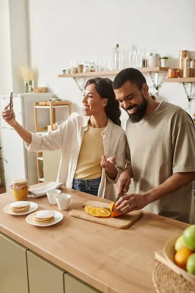 A joyful couple shares laughter while preparing breakfast in their cozy kitchen, creating memories. — Stock Photo