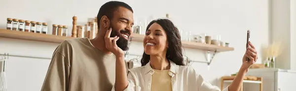 A couple shares a joyful moment together in their cozy home while taking a playful selfie. — Stock Photo