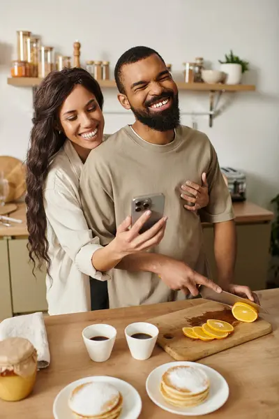 A couple enjoys each others company while making breakfast in their cozy kitchen. — Stock Photo