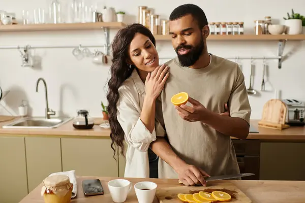 Couple enjoys each others company while slicing fresh oranges in their warm and inviting kitchen. — Stock Photo
