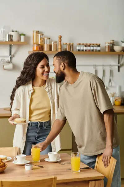 Una pareja feliz disfruta de un desayuno cariñoso juntos en su cálida y acogedora cocina. - foto de stock