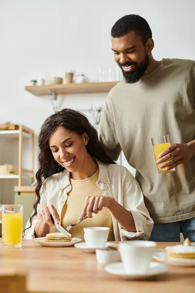 A couple shares laughs and pancakes together at home, enjoying a cozy breakfast. — Stock Photo