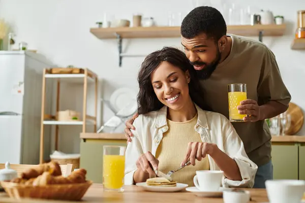 Una pareja disfruta de un desayuno caliente juntos, lleno de risas y amor en su casa. - foto de stock