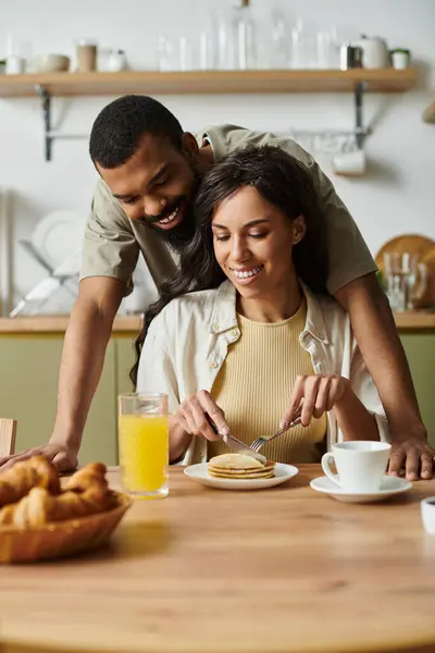 Loving couple shares smiles and pancakes over a cozy breakfast at home. — Stock Photo