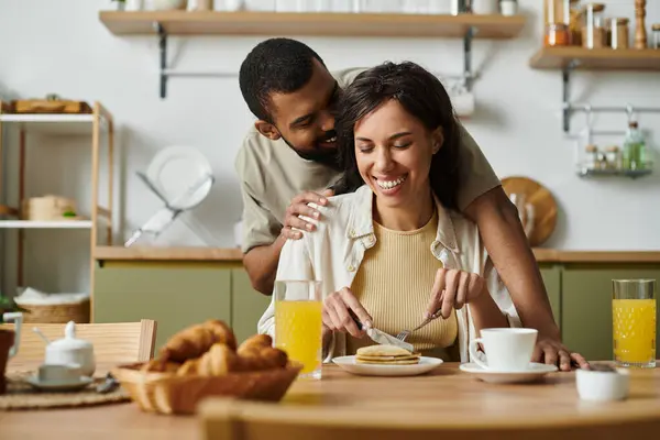 En una cocina caliente, la pareja comparte la risa y el desayuno mientras saborea su conexión. - foto de stock