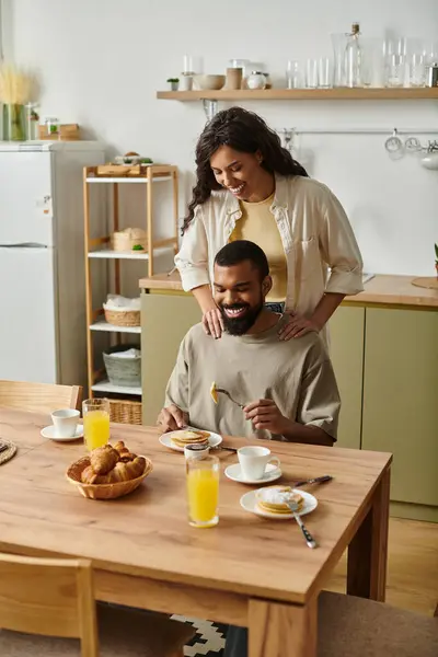 Una coppia gioiosa condivide una colazione calda a casa, piena di risate e amore nell'aria. — Foto stock
