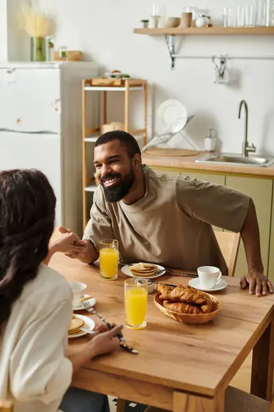 Una pareja cariñosa comparte el desayuno, la risa y el calor en su acogedor hogar. - foto de stock