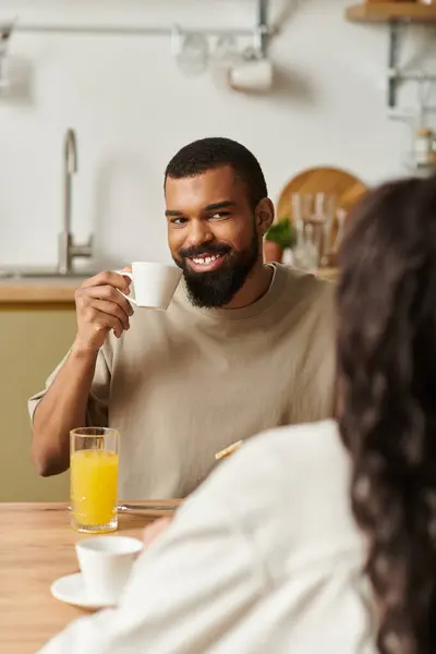 A couple enjoys a warm morning together, sipping coffee in their inviting kitchen while smiling. — Stock Photo