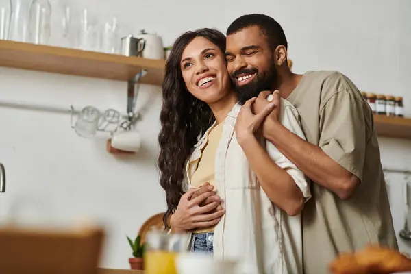 Una pareja feliz se abraza en una acogedora cocina, compartiendo el amor y disfrutando de su tiempo juntos. - foto de stock
