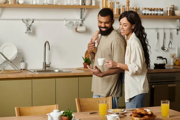 A happy couple shares coffee and smiles in their cozy kitchen. — Stock Photo