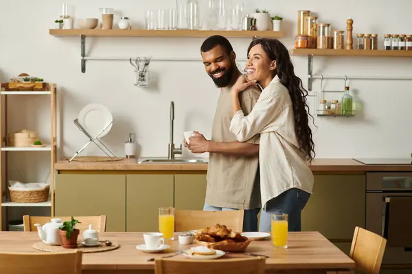 A joyful African American couple hugs in their kitchen while enjoying breakfast together. — Stock Photo