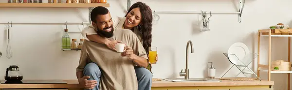 Радостная пара разделяет любящий момент, наслаждаясь напитками в их уютном кухонном пространстве. — стоковое фото