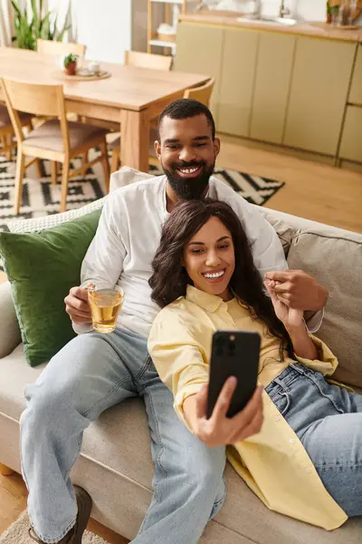 A happy African American couple is enjoying quality time together, taking selfies on the couch. — Stock Photo