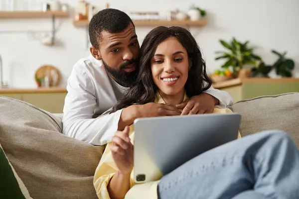 A couple enjoys laughter and joy while exploring content on a tablet in a cozy place. — Stock Photo