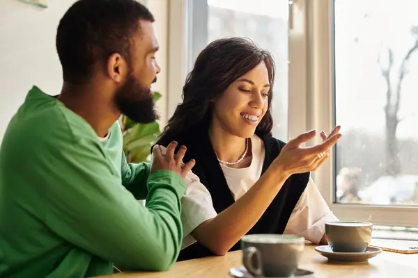 A couple shares laughter and conversation over coffee on a sunny day. — Stock Photo