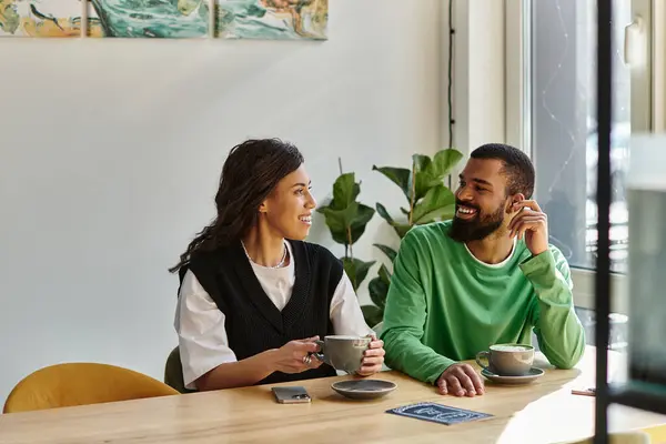 An African American couple enjoys warm beverages and sweet conversation in a cozy cafe setting. — Stock Photo
