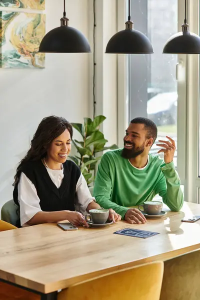 Bright morning in a stylish cafe as a couple shares laughter over coffee and pastries. — Stock Photo