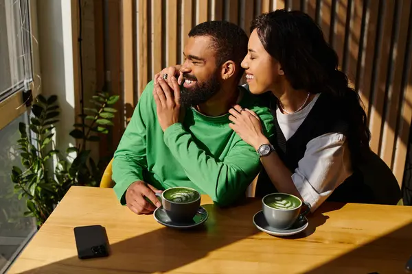 An African American couple sits closely in a cafe, enjoying their drinks and each others company — Stock Photo