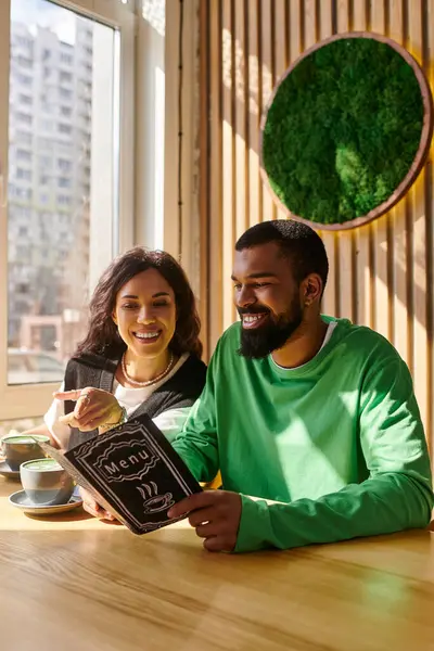 An African American couple shares a heartfelt moment at a cafe, looking at the menu. — Stock Photo