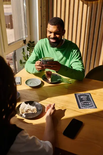 An African American couple savors desserts and drinks in a cafe, sharing laughter and joy. — Stock Photo