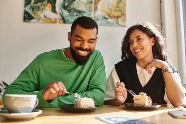A happy couple relishes delicious desserts while seated in a warm cafe atmosphere. — Stock Photo