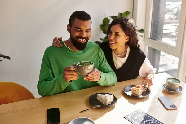 Una coppia felice si gode caffè e dessert insieme in un incantevole caffè, condividendo sorrisi e risate. — Foto stock