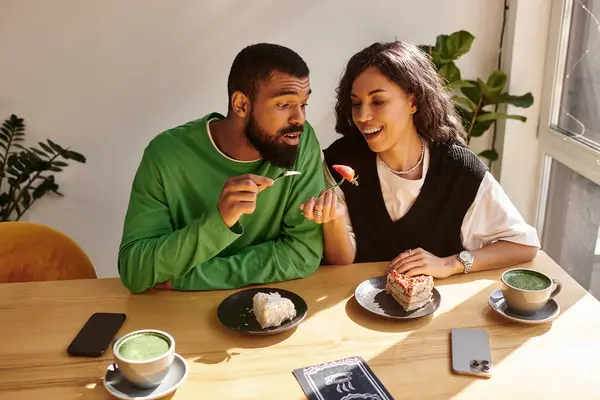An african american couple enjoys dessert and drinks while sharing smiles and laughter. — Stock Photo