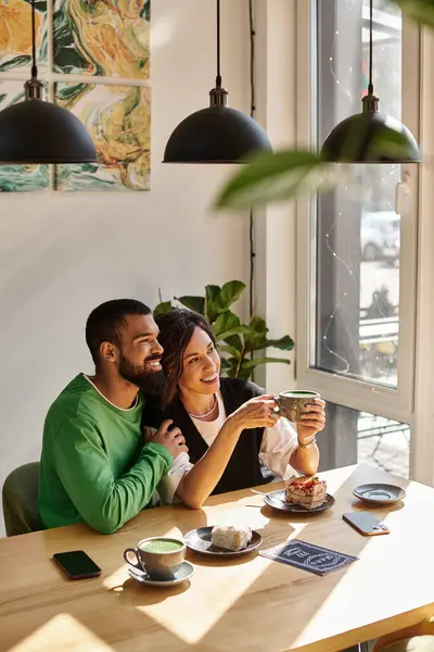 Lively couple shares laughter and coffee in a bright cafe, enjoying each other's company. — Stock Photo