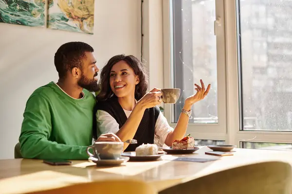 A couple shares laughter and conversation over coffee in a warm, inviting cafe. — Stock Photo