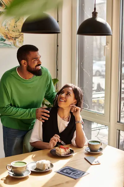 A joyful African American couple enjoys dessert and drinks while smiling at each other in a cafe. — Stock Photo