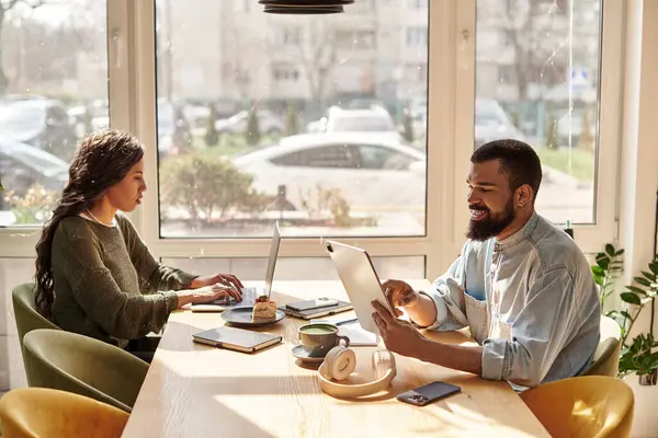 An African American couple collaborates on freelance projects in a vibrant cafe setting. — Stock Photo