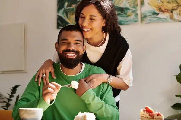 A happy couple enjoys dessert together in a warm cafe atmosphere, surrounded by plants. — Stock Photo