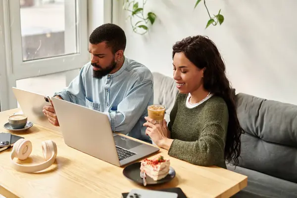 Una pareja disfruta trabajando juntos en un café, participando en proyectos independientes mientras bebe. - foto de stock